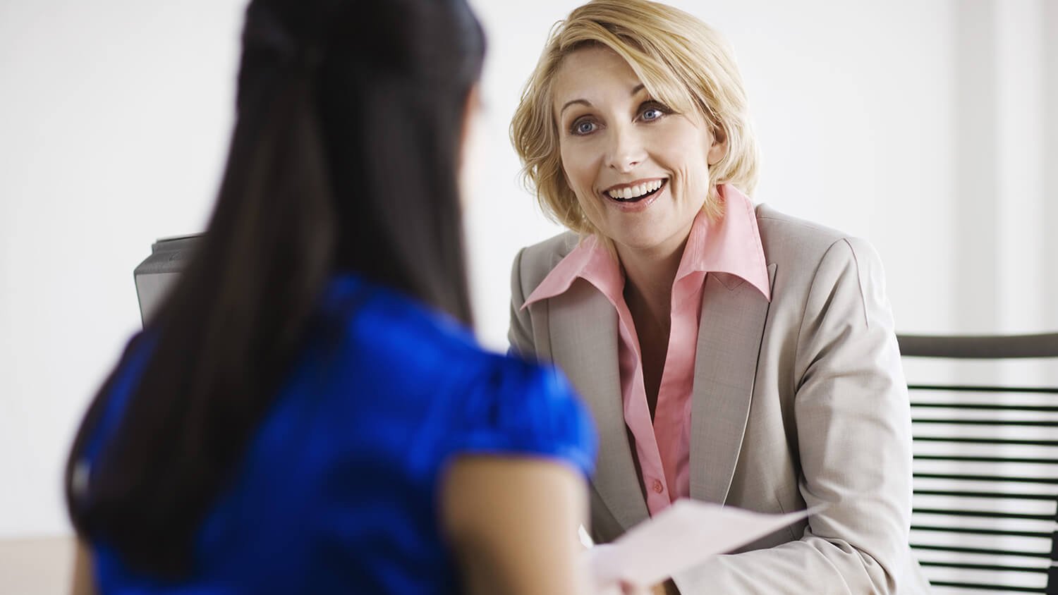 A happy older woman is talking to a younger woman at a table