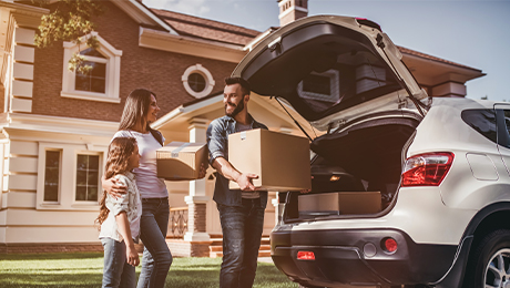 young family unloading moving boxes from truck