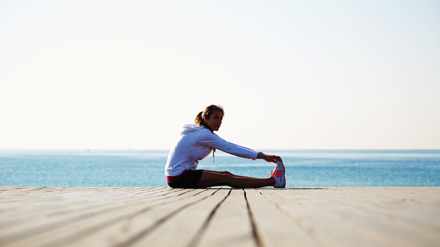 running stretching on a boardwalk by the shore