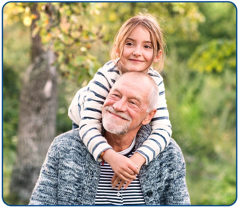 grandfather with granddaughter on his shoulders outside