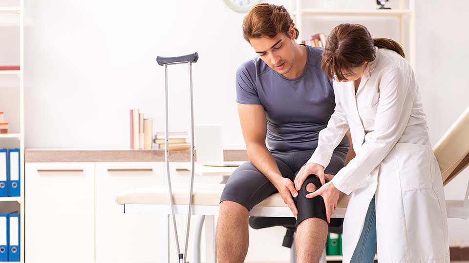 young man having his knee examined by a doctor