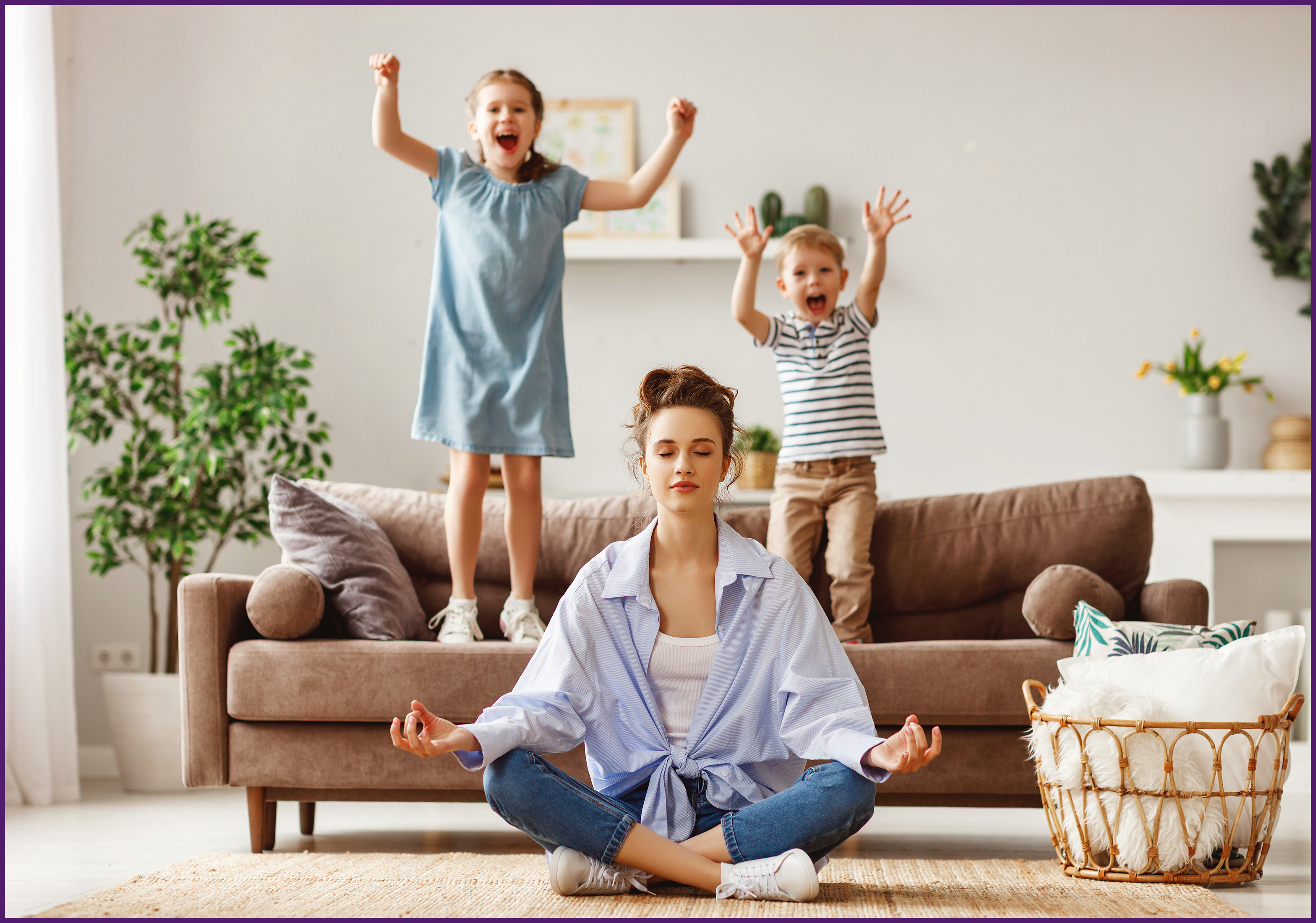image of a mother sitting on the floor while her two children jump on the couch