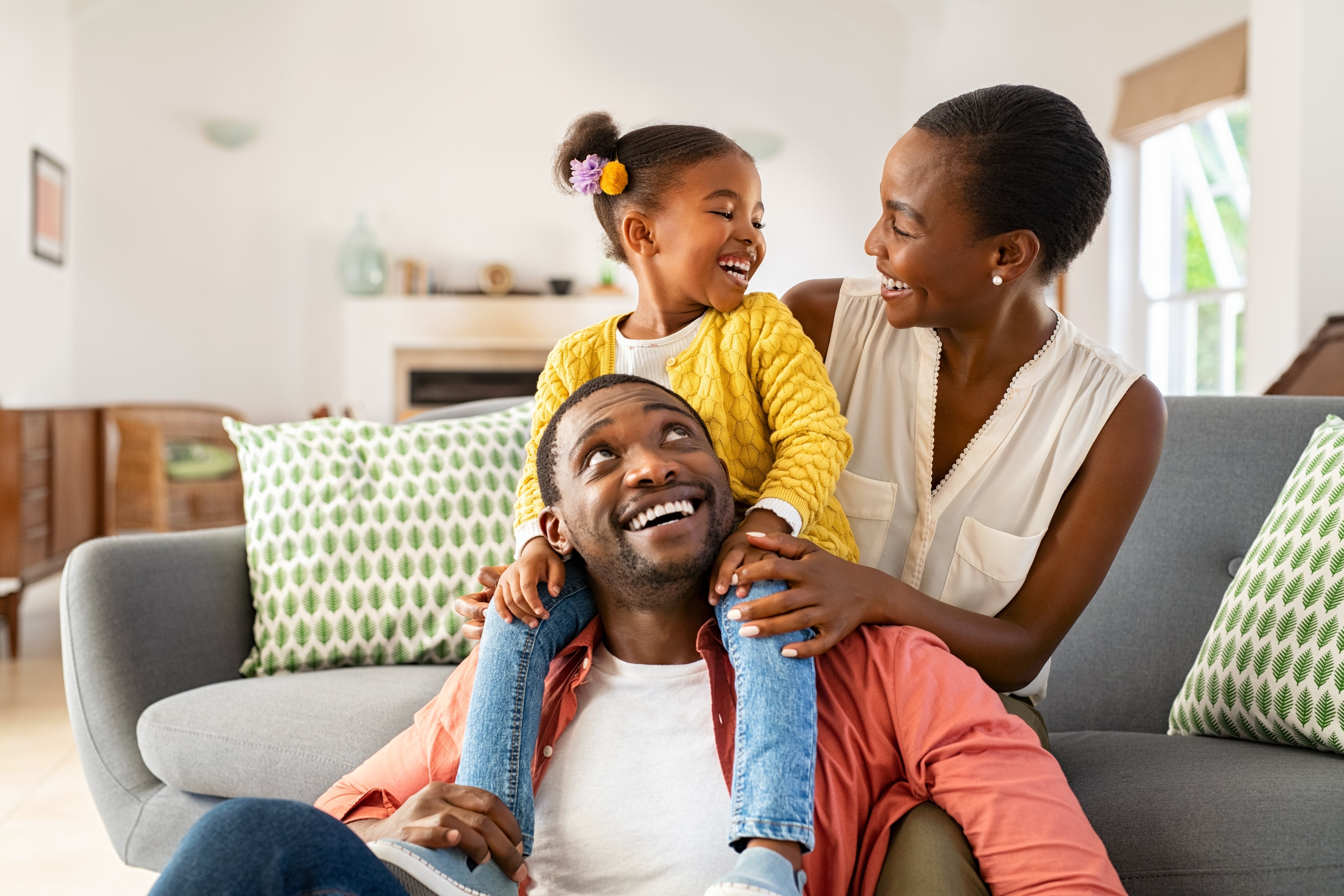 image of a mother, father and daughter sitting on the couch playing
