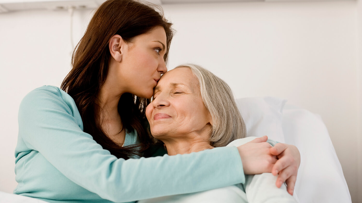 Young woman hugging her mother on a hospital bed