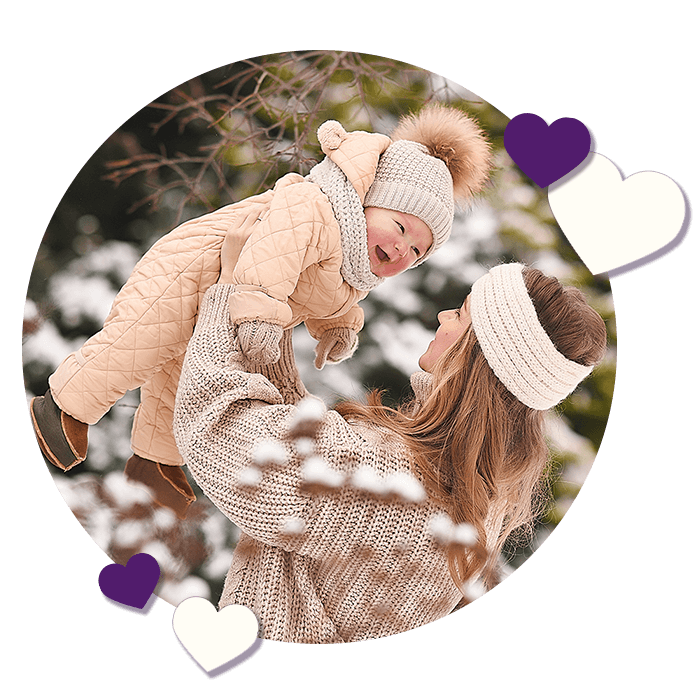 circle shaped photo of mother and baby in snow gear with hearts around the photo